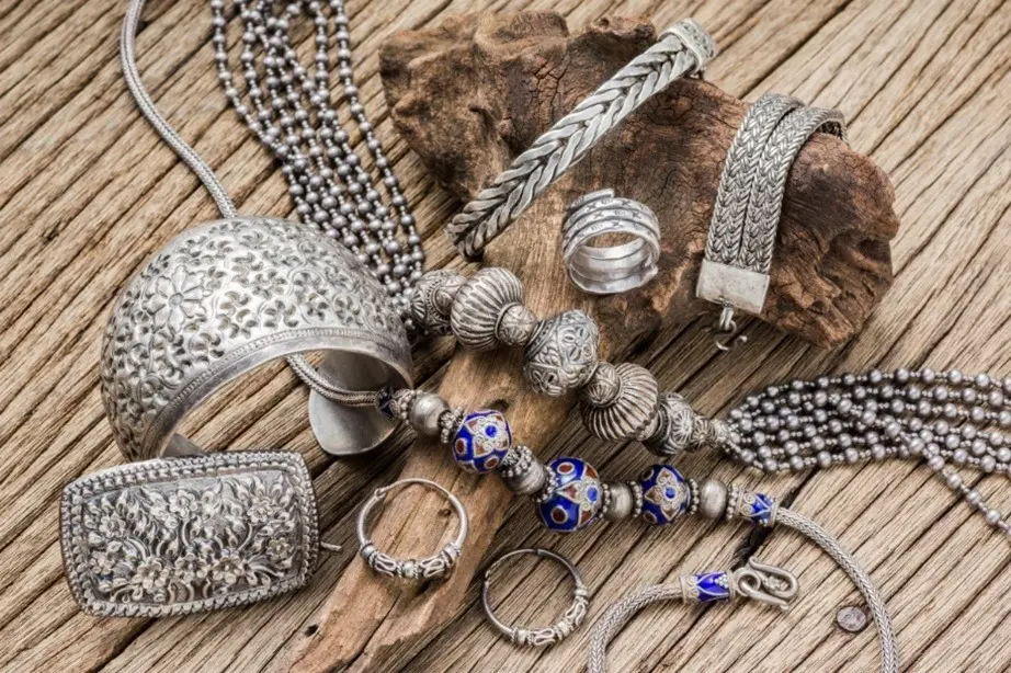 A bunch of silver jewelry on top of a wooden table.