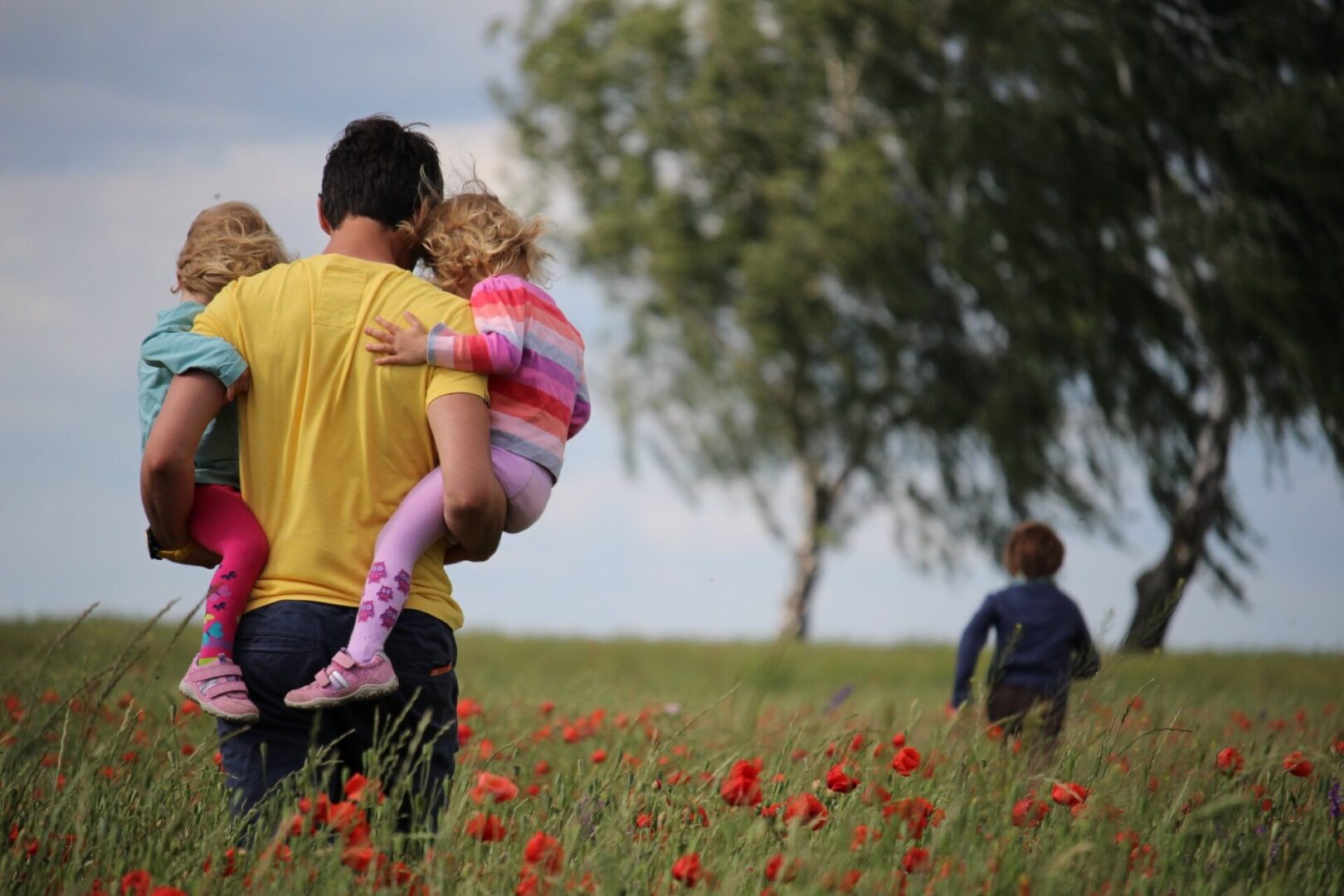 A man holding two children in his arms.