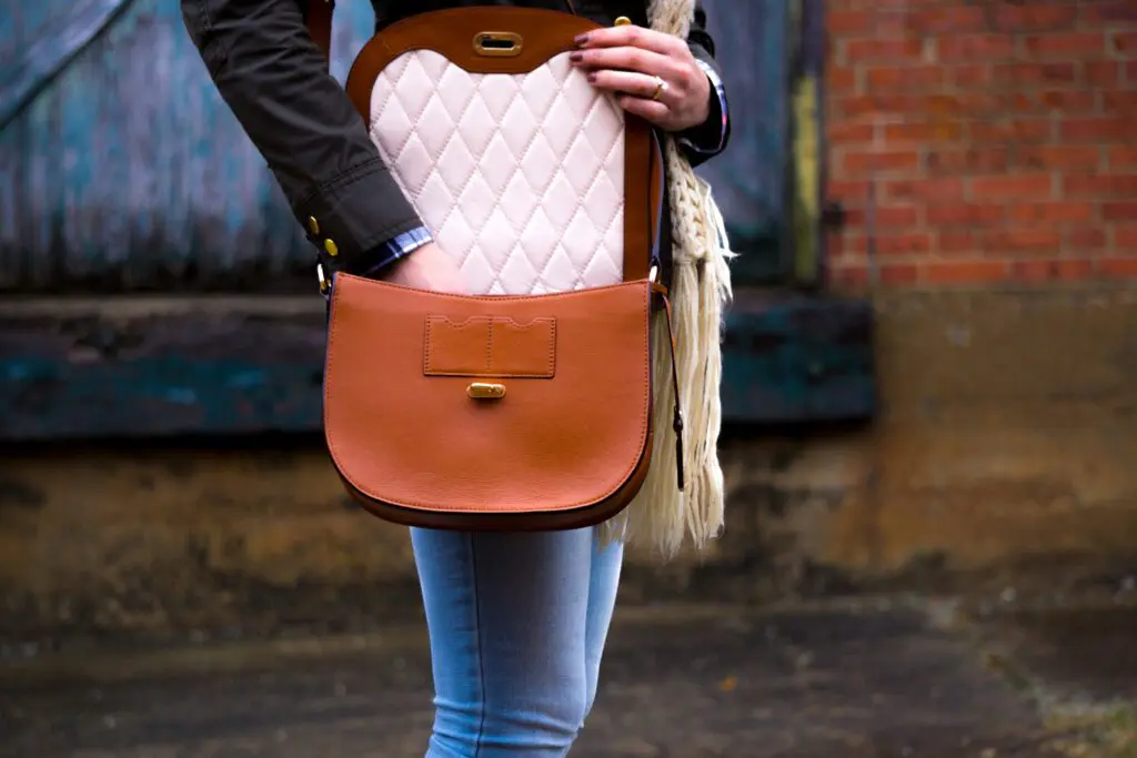 A lady with a brown leather bag with her hand in it.