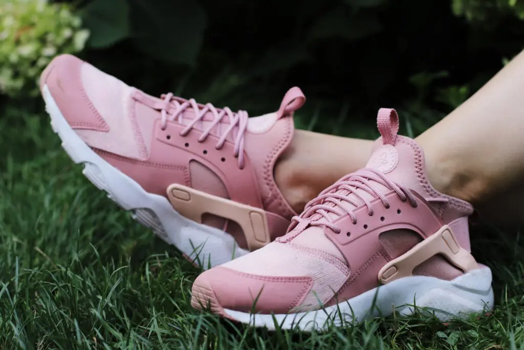 A pair of pink sneakers sitting in the grass.