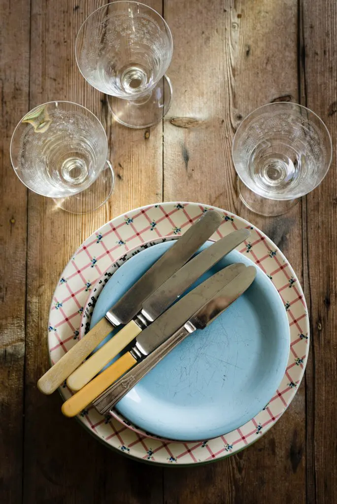 A blue plate with four knives and two glasses