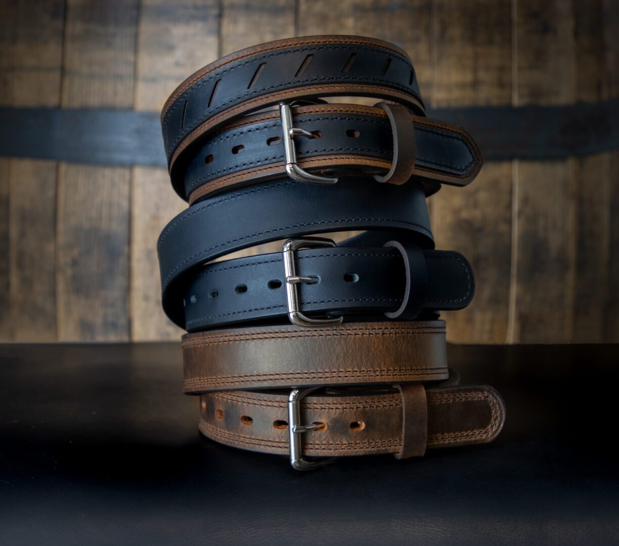 A stack of four leather belts on top of each other.